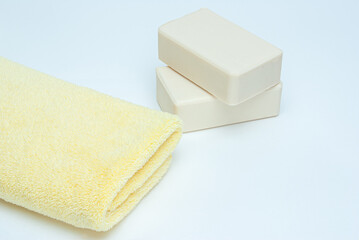 Purity concept concept. Yellow towel and white soap on white background.