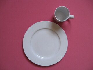 plato grande plano blanco de servir  con taza blanca honda tipo mug en esquina superior derecha sobre fondo rosa
