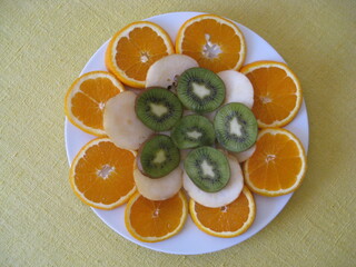 rodajas de diversas frutas, naranja, pera y encima kiWis sobre plato blanco. Frutas de agua, y c&iacute;tricas para zumos,
