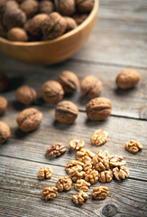 Fresh walnut kernels and whole walnuts in a bowl on rustic old wooden table. Healthy organic food, BIO viands, natural background. Copy space for your advertising text message