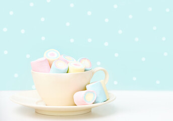 
Marshmallows in a beige mug on a white wooden table