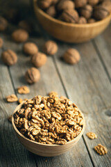 Fresh walnut kernels and whole walnuts in a bowl on rustic old wooden table. Healthy organic food, BIO viands, natural background. Copy space for your advertising text message