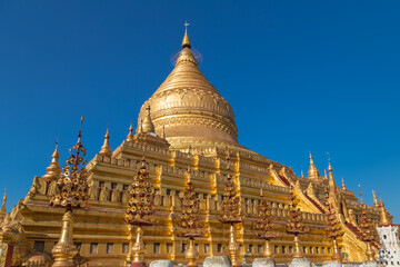 Naklejka premium Shwezigon pagoda is the only fully coated by gold bell shaped Buddhist stupa in Bagan, Myanmar, a prototype for all Burmese stupas. Shwezigon paya enshrines Buddha tooth and bone relics