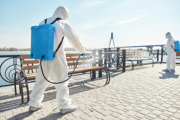 Nobody does it better. Sanitization, cleaning and disinfection of the city due to the emergence of the Covid19 virus. Specialized team in protective suits and masks at work near the riverside