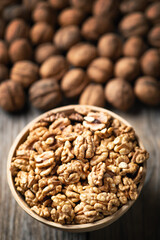 Fresh walnut kernels and whole walnuts in a bowl on rustic old wooden table. Healthy organic food, BIO viands, natural background. Copy space for your advertising text message
