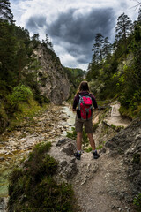 Naklejka na ściany i meble Young Girl Hiking Beneath Clear And Wild Mountain River In Green Canyon In Ötschergräben In Austria