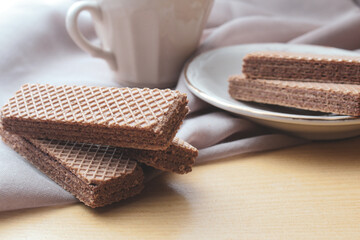 chocolate wafers and cup of milk, on brown cloth background