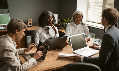 Brainstorming of Diverse group employees working together on a new business project. Young African girl, an elderly gray-haired Asian woman and two Caucasian young men share their ideas.