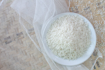 Raw white rice in white plate, on croton and winnowing tray