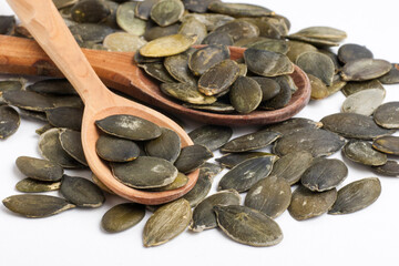Pumpkin seeds on two wooden spoons on a white background.