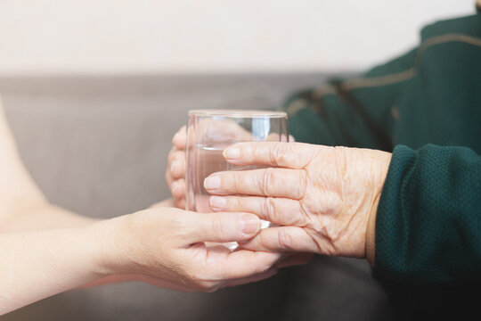 Grandmother with a glass of water, granddaughter gives grandmother a glass of water