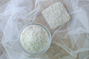 raw white rice in bowl, on croton and winnowing tray background