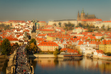 Fototapeta na wymiar Tilt Shift Photography View of Charles Bridge and Prague Castle. Aerial view of the rooftops of Prague.