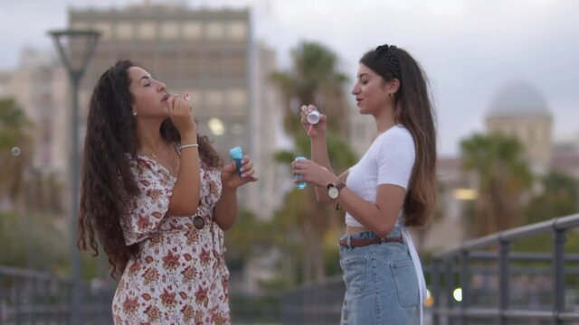 Young multi-ethnic women having fun blowing bubbles together, slow motion