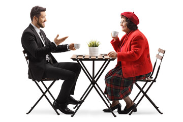 Young man in a suit sitting in a cafe with an elderly woman and talking