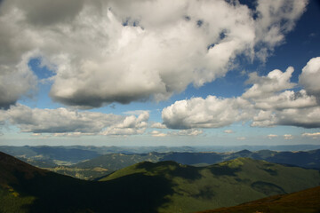 Fototapeta premium View of the valley from the top of the mountain on a background of several mountains and the sky with clouds