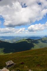 View of the valley from the mountain top on a background of mountains and blue sky with clouds