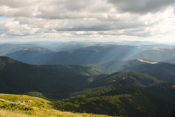 Obraz premium View of the valley from the top of the mountain on a background of several mountains and the sky with clouds