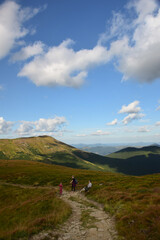 Several travelers walking along the ridge to the top of the mountain against the sky