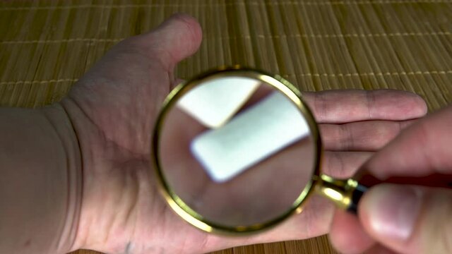 Studying Gum Under A Magnifying Glass Man With White Hands Two Pads On A Brown Background, View From Above