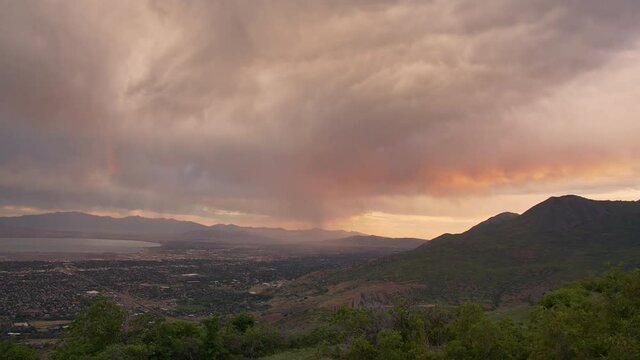 Storm moving over valley during sunrise time lapse in Utah as colors change in the clouds.