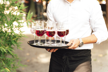 Man carrying tray with several various colorful drinks. Waiter serving beverages. Celebration,...