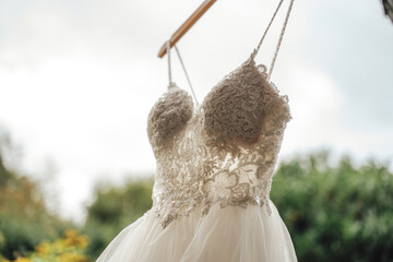 Close up of laced chest part of wedding dress against sky and green vegetation background. Wedding day concept.
