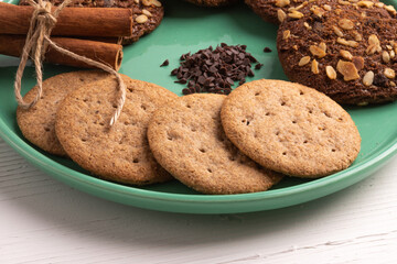Stack of tasty chocolate cookies on white wooden table.