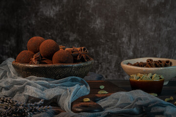 Craft chocolate truffles on plate with cocoa powder and anise, cinnamon, cardamom.