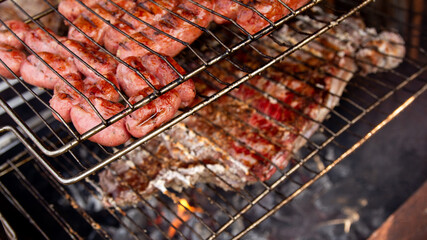Sausage and meat on the grill. Using charcoal to barbecue. Detail of home food being cooked.