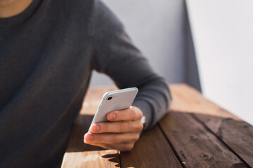 chico joven utilizando su teléfono inteligente con su mano izquierda para enviar un mensaje