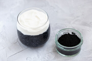 Black chia seed pudding with almond milk, yogurt, activated charcoal powder, dessert in a glass. Superfood, vegan, vegetarian food, detox concept. Gray background. Copy space, closeup, selective focus