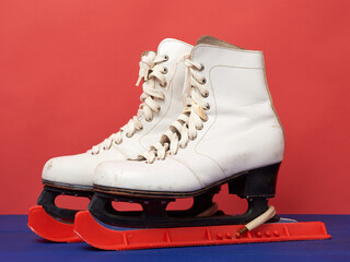 white leather skates for figure skating stand on a red background