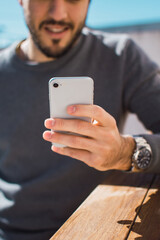 joven utilizando su celular con la mano izquierda y realizando una videollamada 