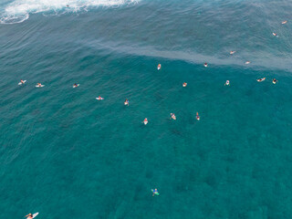 AERIAL: Flying over group of surfers patiently waiting in line up for new waves.