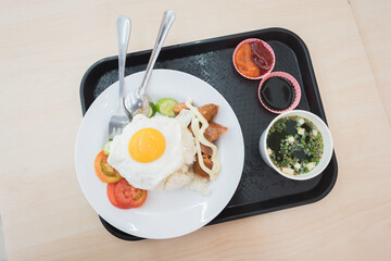 Meal at chain convenience store: fried egg and rice, a sausage, seaweed soup & fresh veggies. A closeup, a top-down view of plates on a tray.