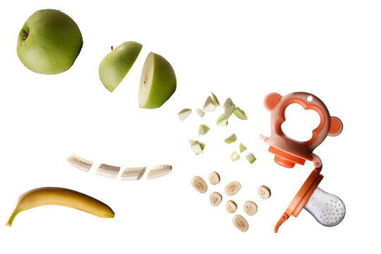 banana and apple slicing falling into the baby nibbler isolated white with copy space