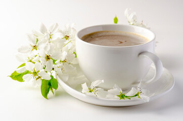 White cup of coffee on a white background, white spring flowers