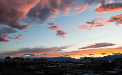 Turin,Piedmont,Italy. May 2020. In the northern suburbs of the city a breathtaking sunset with clouds in warm and bright colors.The mountains of the Alps are on the horizon. The pillars of the stadium