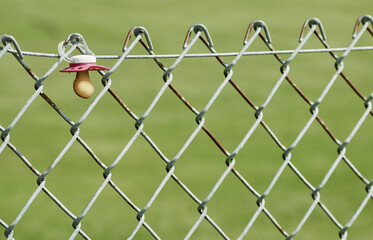 Baby pacifier hangs on a wire-mesh fence