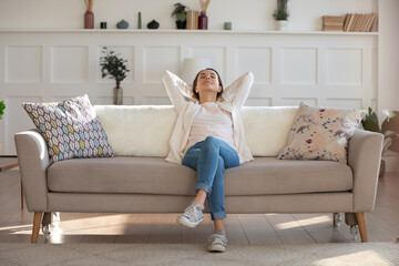 Happy calm young Caucasian woman relax on comfortable modern sofa in living room nap or sleep,...