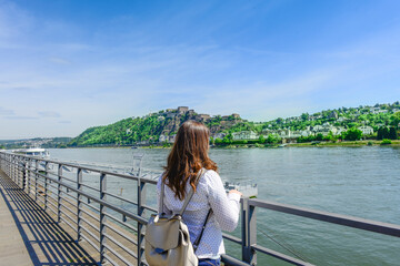 Young Woman Standing On Promenade By River In City During Summer