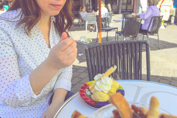 Smilling beautiful girl eating big ice scream with the spoon outside on the table