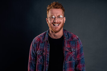 Take this ugly thing away from me. Displeased intense redhead mature guy in glasses and checkered shirt, turning away and protecting face with raised hands, seeing something disgusting over grey wall