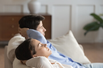 Close up of young caucasian man and woman relax on comfortable couch at home sleeping or taking nap, millennial couple rest on sofa, breathe fresh air, relieve negative emotion, stress free concept