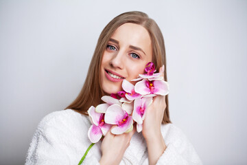 Obraz na płótnie Canvas Facial care. Young woman with beautiful skin holds an orchid