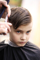 Fototapeta premium Barber cuts the boy with scissors