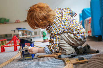a boy playing with a toy wooden railroad