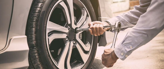 Close up hand of auto mechanic using wrench to changing a car tire. concepts of car insurance support, repair and services. © Eakrin