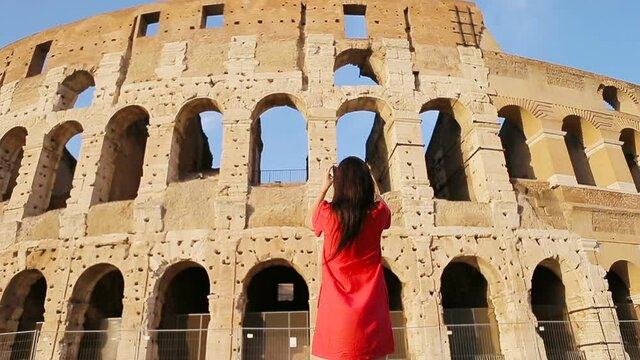 Young woman taking photos in front of colosseum in Rome, Italy. Girl making photographs fo the memory of most popular destination in the world